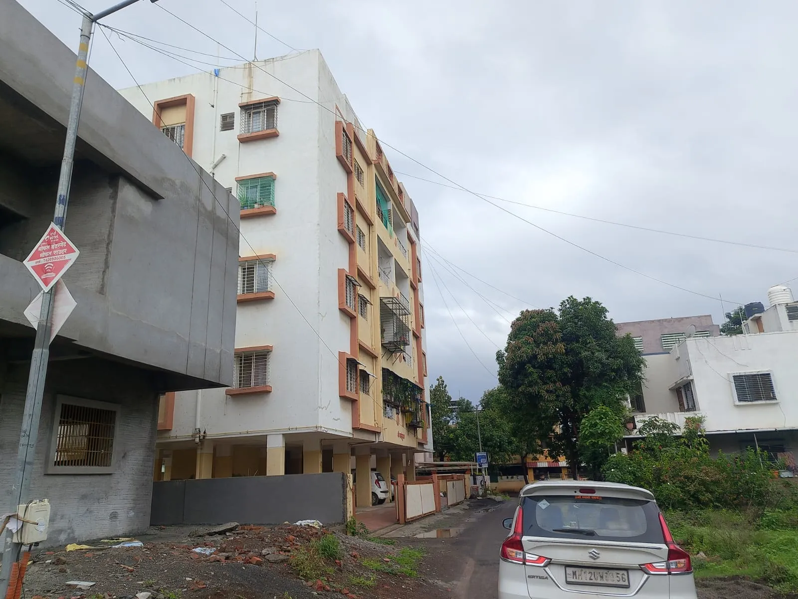 Adgaon plot site with the internal road and an adjacent residential building, Gut No. 551