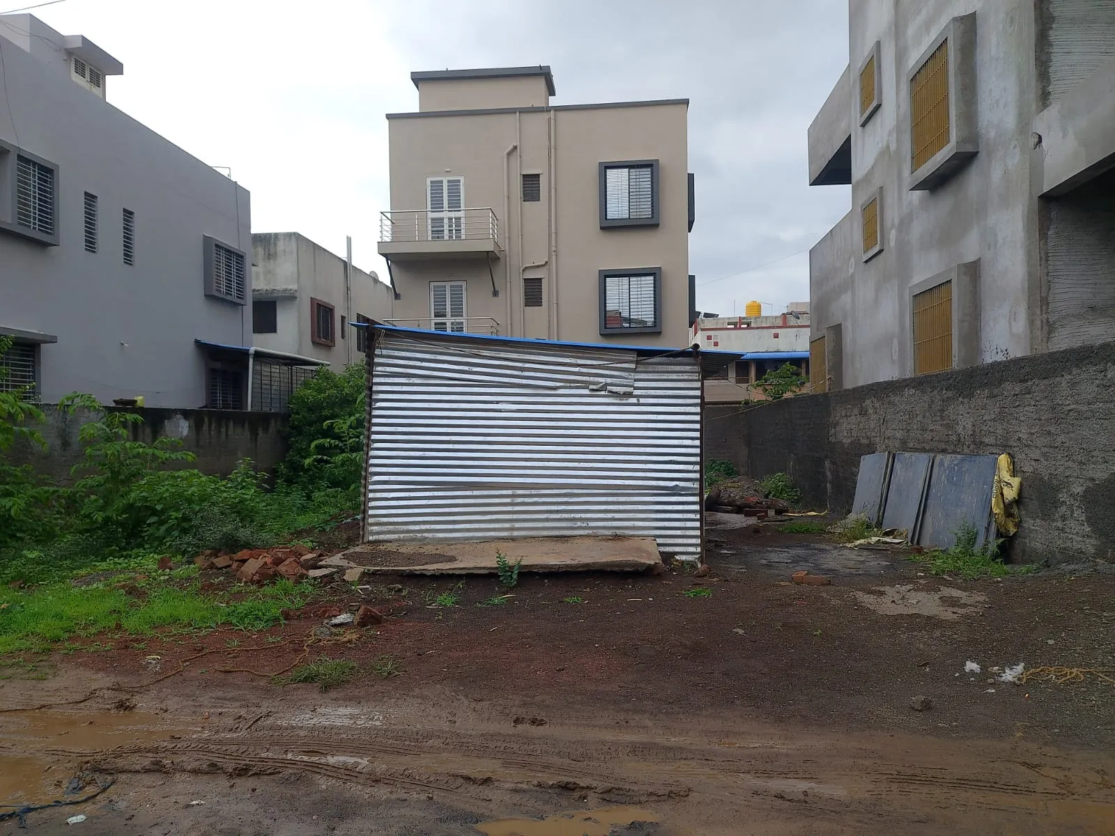 The vacant residential plot in Gut No. 552, Adgaon, bordered by completed bungalows and buildings