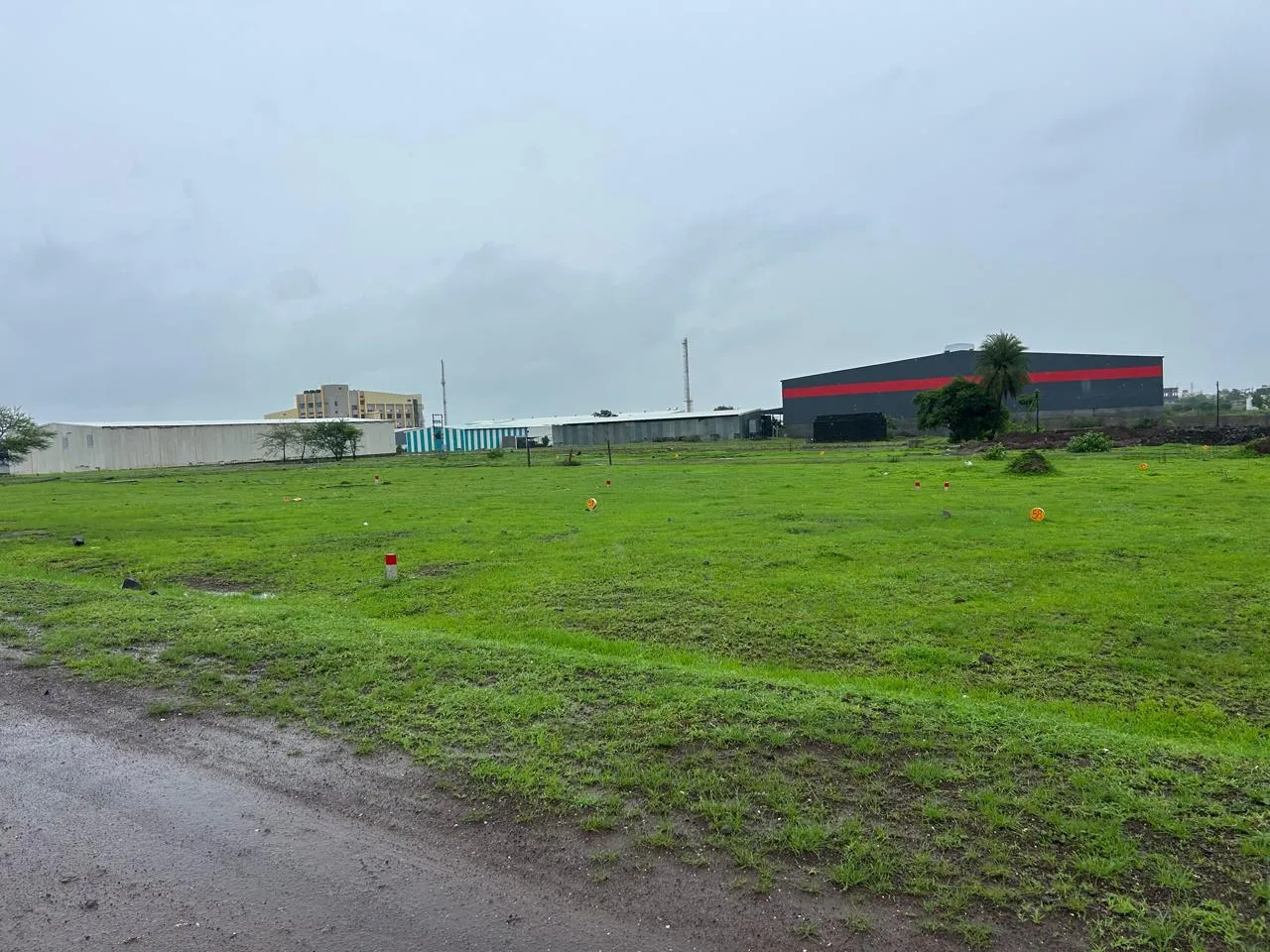 Demarcated residential plots at Jaulke, Dindori, Nashik with boundary markers and industrial units in the background